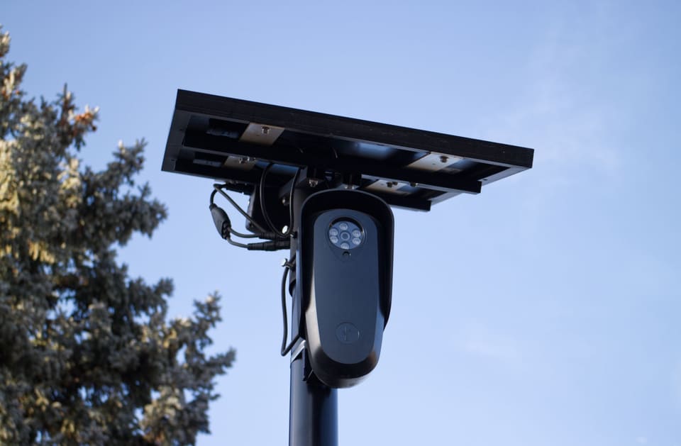 A solar-powered outdoor surveillance camera mounted on a pole, capturing clear day images.